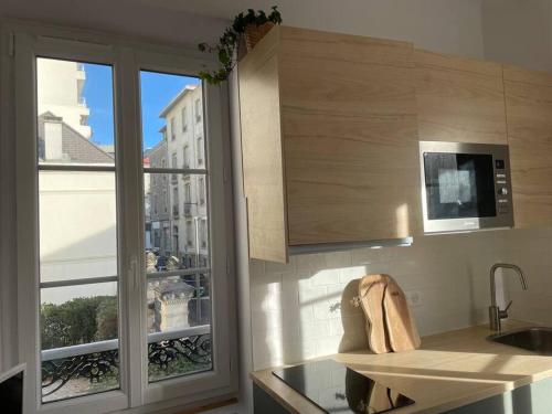 cocina con fregadero, microondas y ventana en Studio Biarritz 2 min Halles, 3 min plages, plein centre. en Biarritz