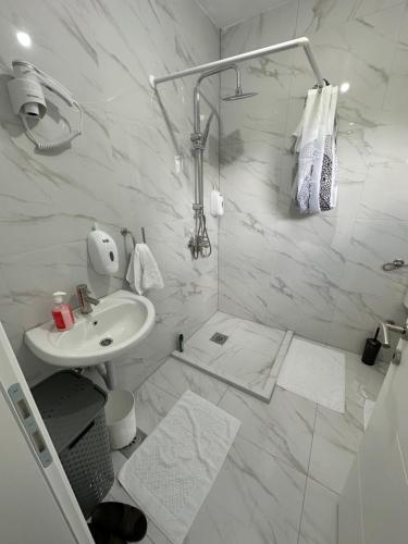 a white bathroom with a sink and a shower at CIOM Apartment in Matuzići