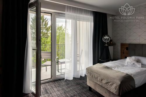 una camera con letto e balcone di Hotel Polonia PARK Medical Center & Spa a Busko-Zdrój