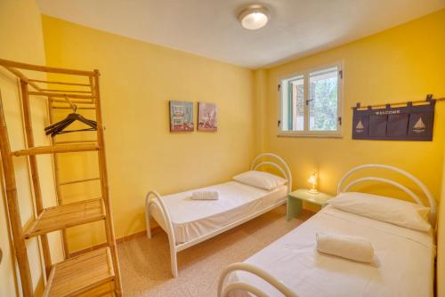 two beds in a room with yellow walls at Casa Vacanza Sole & Luna in Stintino