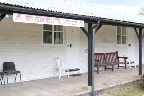 a porch with two benches and a sign on a house at St George's Lodge, Bisley in Brookwood