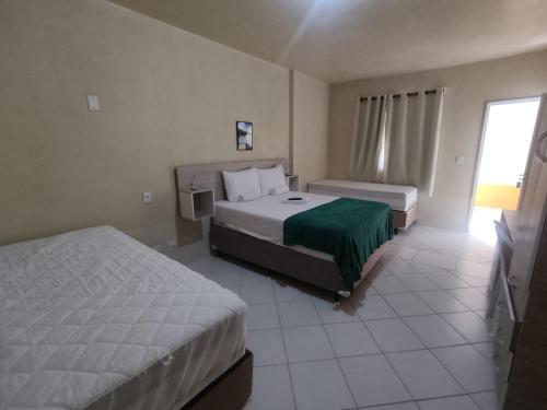 a hotel room with two beds and a window at Amazônia Praia Hotel in Tibau