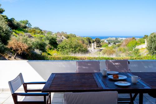 een houten tafel met borden eten op een balkon bij Calm & Joy - Poseidonia in Posidhonía