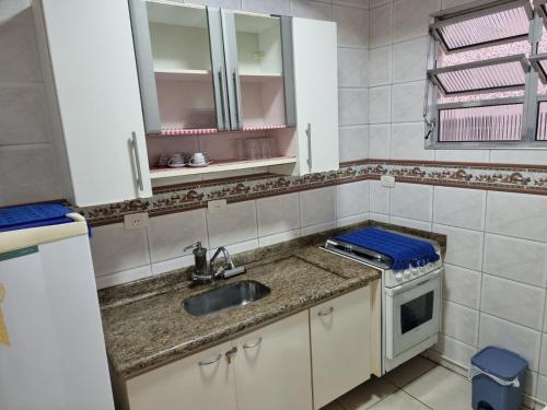 a small kitchen with a sink and a stove at Pé na Areia in Santos