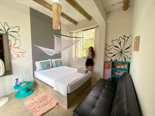 una mujer parada en un dormitorio con una cama y un sofá en Freesoul Hostel en Palomino