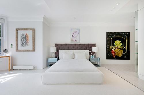 a white bedroom with a large bed and two tables at Lindfield Gardens in London
