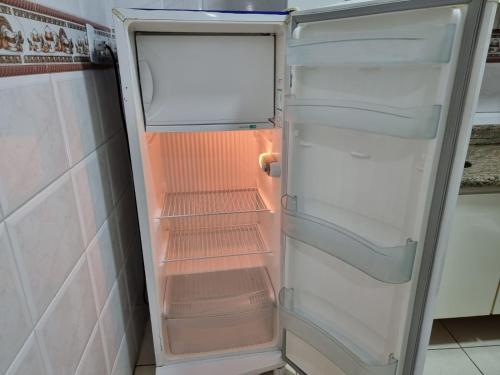 an empty refrigerator with its door open in a kitchen at Pé na Areia in Santos