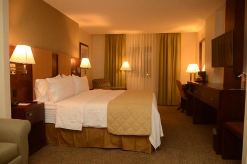 Cette chambre comprend un grand lit avec des oreillers blancs. dans l'établissement Holiday Inn Hotel & Suites Hermosillo Aeropuerto, an IHG Hotel, à Hermosillo
