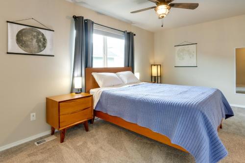 a bedroom with a bed with a blue comforter and a window at Alaska Retreat with Balcony, Near Earthquake Park! in Anchorage