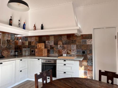 a kitchen with white cabinets and a wooden table at Casa Bizarra in Castanheira de Pêra