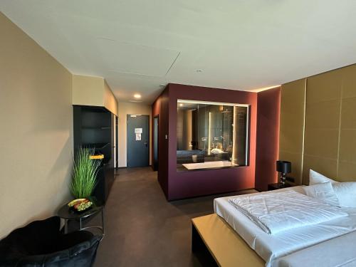 a bedroom with a bed and a chair and a mirror at Primetime Hotel in Gießen