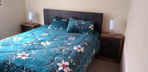 Una cama con un edredón azul con flores. en Apartamento Villarrica, en Villarrica