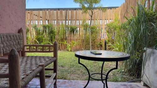 a table and a bench in a backyard with a fence at LDM Appartements Marrakech in Marrakech