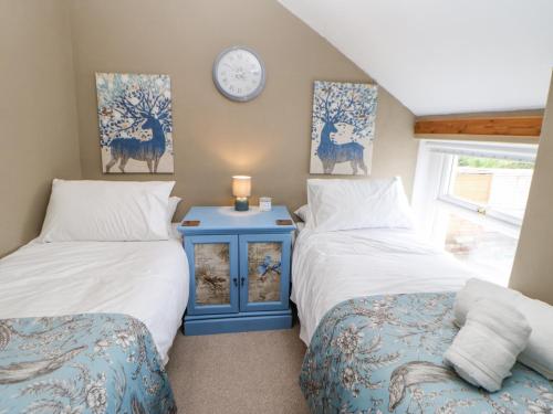 a bedroom with two beds and a clock on the wall at Rock Cottage in Penrith