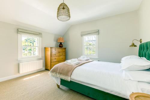 a bedroom with a bed and two windows at Mermaid Cottage in Port Isaac