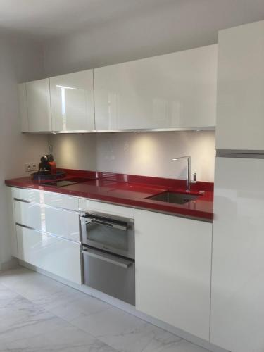 une cuisine avec des placards blancs et un comptoir rouge dans l'établissement Escale à Saint-Tropez, à Saint-Tropez