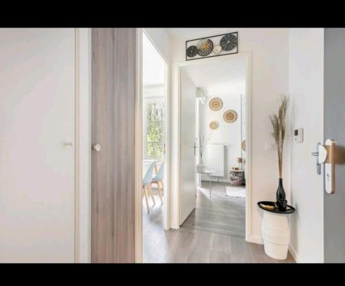 um quarto branco com um corredor com uma mesa e uma sala de jantar em Appartement Cosy à 8 min Disney 20 min Paris em Montévrain