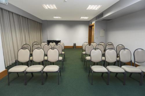 a room with a bunch of chairs in front of a screen at Golden Tulip Porto Vitória in Vitória