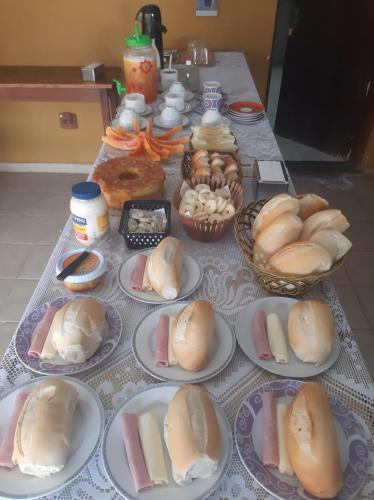 Una mesa cubierta con platos de perritos calientes y otras comidas. en Pousada Morada Dusanjos, en Caraguatatuba