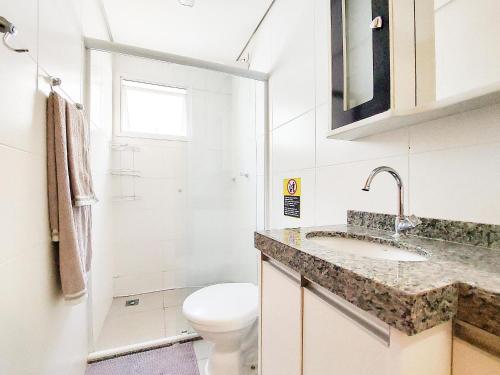 a white bathroom with a toilet and a sink at Apto 3 quartos, sacada, churrasqueira e garagem in Londrina