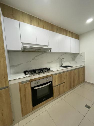 a kitchen with white cabinets and a stove and a sink at HABITACION DE LUJO CON BAÑO PRiVADO in Valledupar