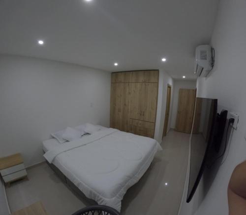 sypialnia z białym łóżkiem i drewnianą szafką w obiekcie HABITACION DE LUJO CON BAÑO PRiVADO w mieście Valledupar