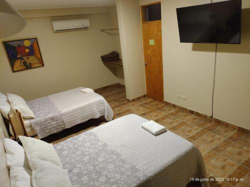 a room with two beds and a flat screen tv at Hotel El Huacachinero in Ica
