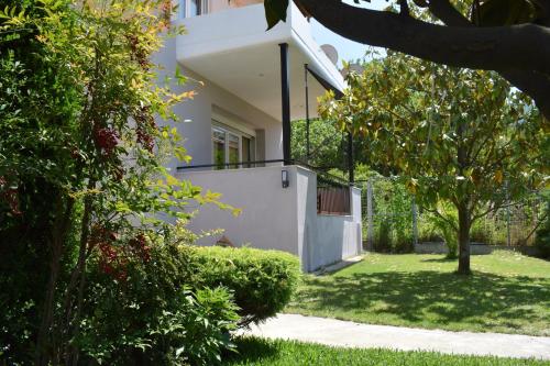 une maison blanche avec une cour avec de l'herbe et des arbres dans l'établissement Nakis Apartment All Seasons, à Stavros