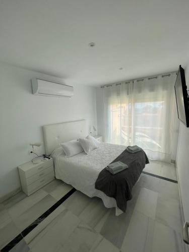 een witte slaapkamer met een bed en een raam bij Apart 3 EN PRIMERA LÍNEA DE PLAYA CON TERRAZA Y VISTAS AL MAR in Almería