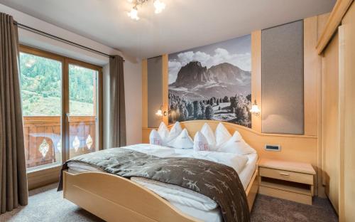 een slaapkamer met een bed en een groot raam bij Hotel Carmen in Santa Cristina in Val Gardena
