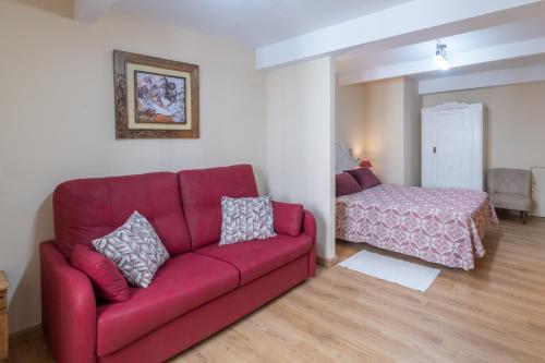 a living room with a red couch and a bed at Belmonte, apartamento en Ribadesella in Ribadesella
