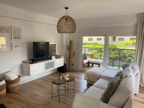 ein Wohnzimmer mit einem weißen Sofa und einem TV in der Unterkunft Appartement boho chic près de la plage in Cambrils