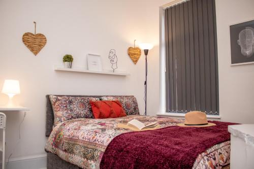 a bedroom with a bed with a book and a hat on it at Enchanting and welcoming space in Aintree