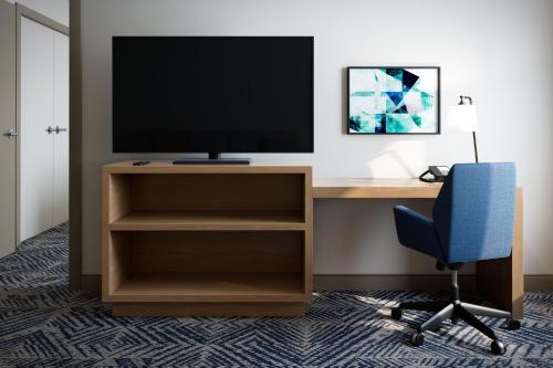 a desk with a television and a blue chair at Candlewood Suites DFW Airport North - Irving by IHG in Irving