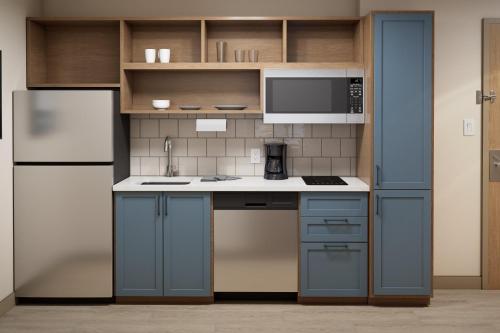 a kitchen with blue cabinets and a refrigerator at Candlewood Suites DFW Airport North - Irving by IHG in Irving