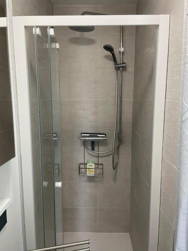 une douche avec une porte vitrée dans une salle de bain dans l'établissement Merlimont-plage: studio, à Merlimont