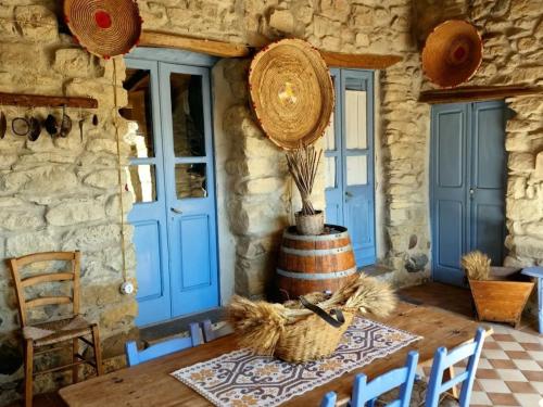 a dining room with a wooden table and a blue door at Sa domu de ziu Antoneddu in Tuili
