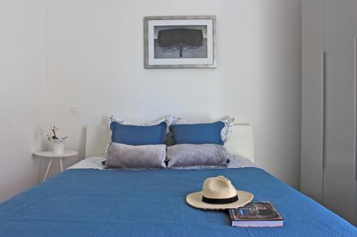 un chapeau et des livres assis sur un lit bleu dans l'établissement Apartment Limoni, à Sutivan