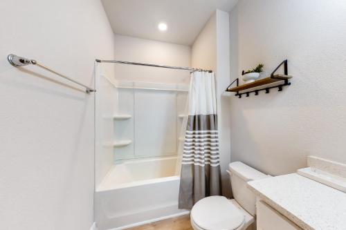 uma casa de banho branca com um chuveiro e um WC. em Windmark - Sea Grove Guesthouse em Saint Joe Beach