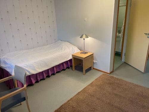a small bedroom with a bed and a table with a lamp at Grand Hostel Imatra in Imatra