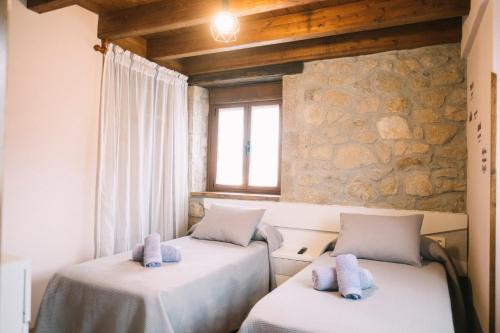 2 camas en una habitación con una pared de piedra en Apartamentos El Valle, en Avín