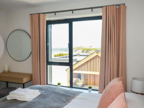 a bedroom with a large window with a view of the ocean at Porth Cove in Newquay