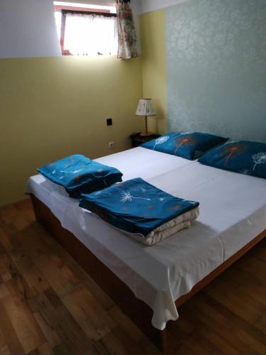 1 dormitorio con 2 camas con sábanas azules y ventana en Tóth nyaraló, en Balatongyörök