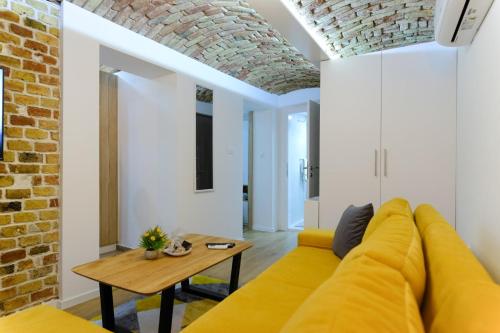 a living room with a yellow couch and a table at All seasons apartments Sarajevo with free parking in Sarajevo