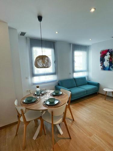 a living room with a table and a blue couch at Coqueto apartamento con garaje in Conil de la Frontera
