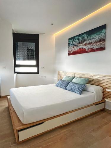 a bedroom with a large white bed and a painting on the wall at Coqueto apartamento con garaje in Conil de la Frontera