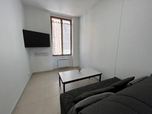 een woonkamer met een bank en een tafel bij Bel appartement à 15 min de Lyon in Saint-Fons