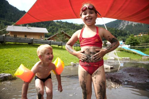 a woman and a child in the water with an umbrella at Familienhotel Lagant in Brand