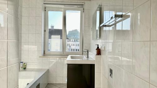 a white bathroom with a sink and a window at Homely Stay Apartment 3 in Sankt Pölten