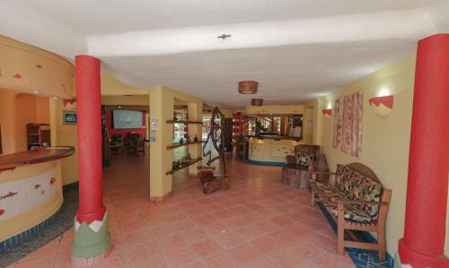 a hallway with red columns in a house with a dog at Estação Santa Fé Hotel e Pousada in Arraial d'Ajuda